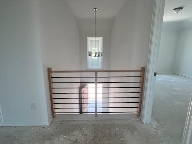 spare room with baseboards, a notable chandelier, and unfinished concrete flooring