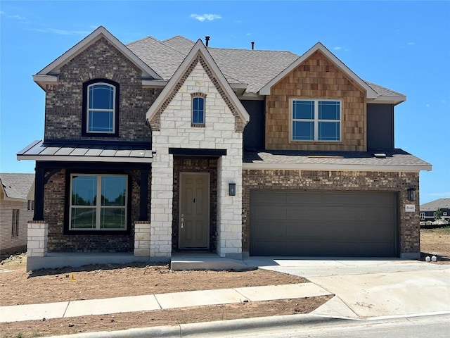 view of front of house featuring a standing seam roof, brick siding, a shingled roof, an attached garage, and driveway