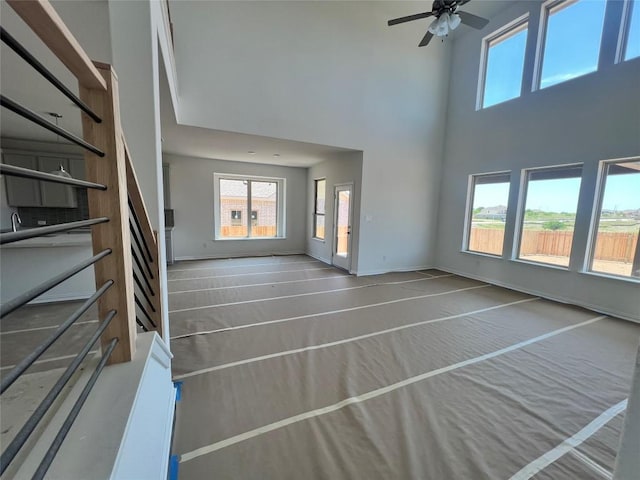 unfurnished living room featuring plenty of natural light, a high ceiling, and stairs