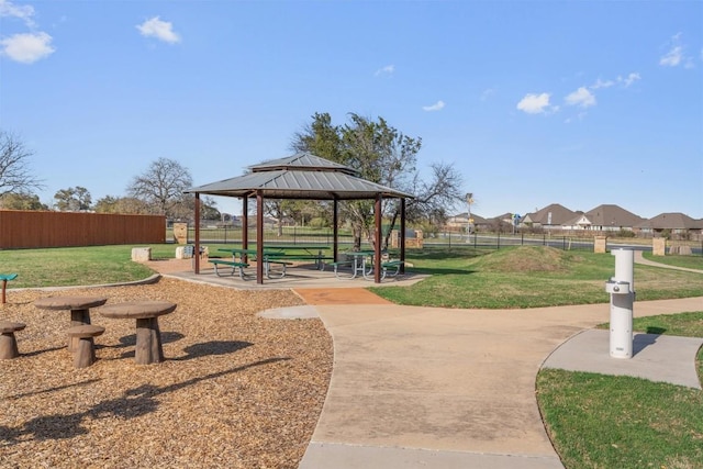 view of community with a gazebo, a lawn, and fence