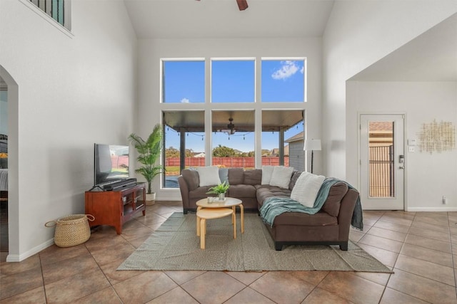 living room featuring baseboards, arched walkways, high vaulted ceiling, and a ceiling fan