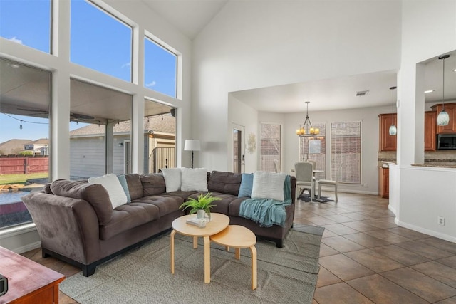 living area with visible vents, a high ceiling, an inviting chandelier, tile patterned flooring, and baseboards