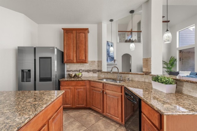 kitchen with a sink, black dishwasher, tasteful backsplash, stainless steel fridge, and light stone countertops