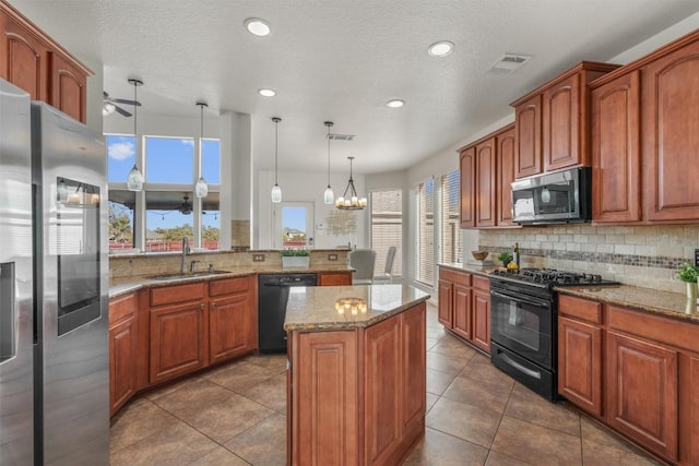 kitchen featuring visible vents, a kitchen island, ceiling fan with notable chandelier, black appliances, and a sink