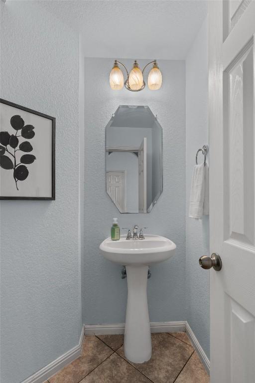 bathroom featuring tile patterned floors, baseboards, and a textured wall