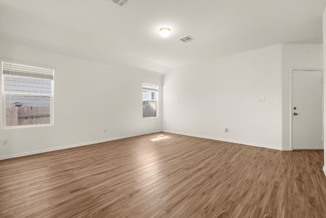 unfurnished room featuring wood finished floors, visible vents, and baseboards