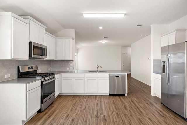 kitchen featuring light wood finished floors, visible vents, a peninsula, stainless steel appliances, and a sink