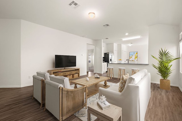 living room featuring visible vents, baseboards, and wood finished floors