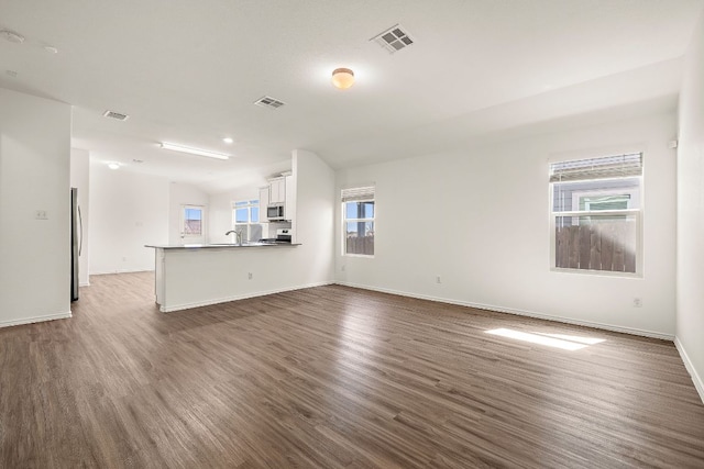 unfurnished living room with visible vents, baseboards, and wood finished floors