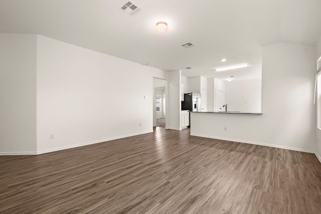 unfurnished living room featuring visible vents, baseboards, and dark wood-style flooring