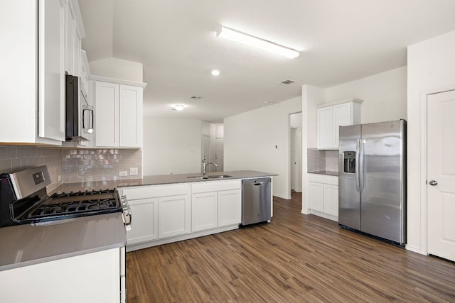 kitchen featuring a sink, appliances with stainless steel finishes, a peninsula, white cabinetry, and dark wood-style flooring