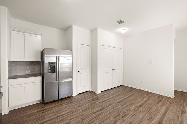 kitchen with visible vents, backsplash, dark wood-style floors, stainless steel fridge, and white cabinets