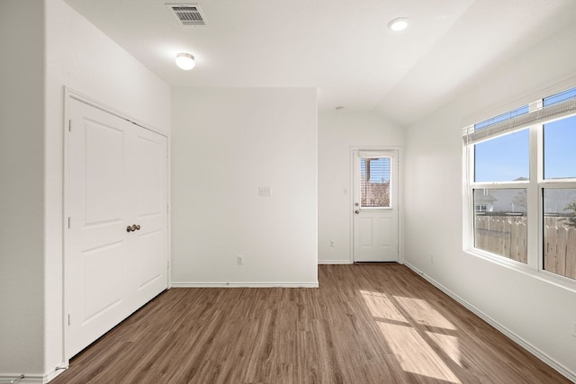 spare room with visible vents, lofted ceiling, baseboards, and wood finished floors