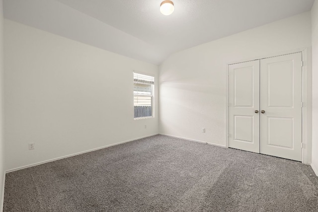 carpeted empty room with lofted ceiling