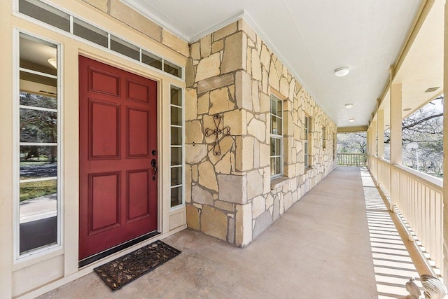 doorway to property featuring stone siding and a porch