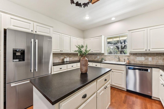 kitchen with a sink, stainless steel appliances, tasteful backsplash, and dark countertops