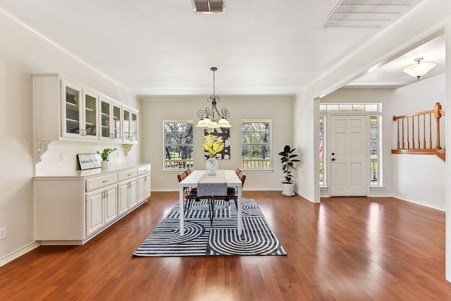 dining space with visible vents, baseboards, ornamental molding, an inviting chandelier, and wood finished floors