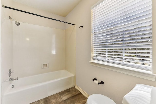 bathroom with bathtub / shower combination, toilet, and baseboards