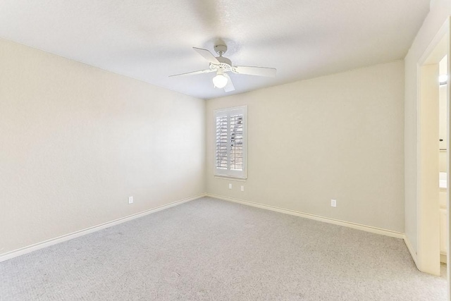 spare room featuring a ceiling fan, baseboards, and light carpet