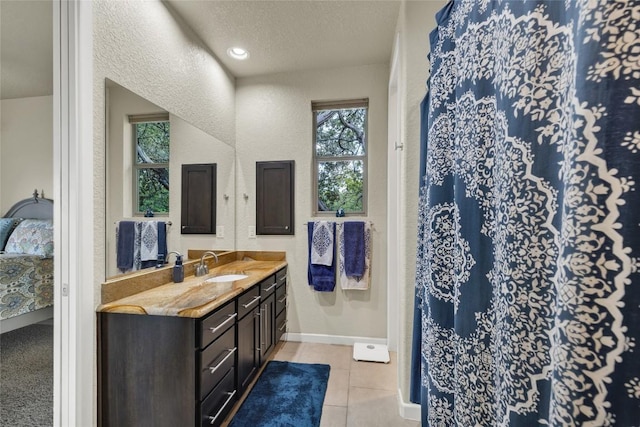 bathroom with tile patterned floors, a textured ceiling, connected bathroom, baseboards, and vanity