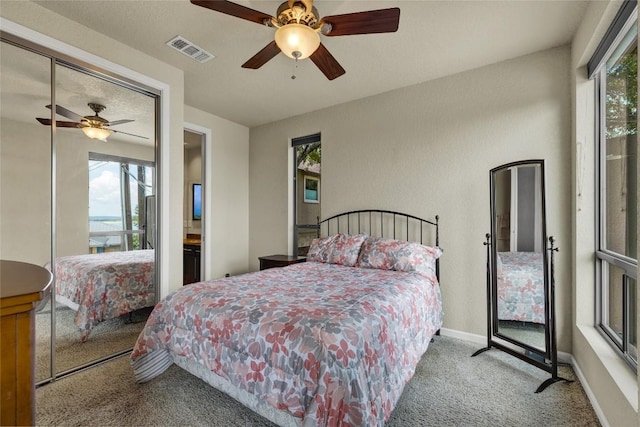 carpeted bedroom featuring visible vents, multiple windows, baseboards, and a ceiling fan