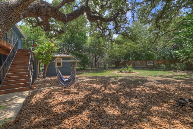 view of yard with stairs, an outdoor structure, and a fenced backyard