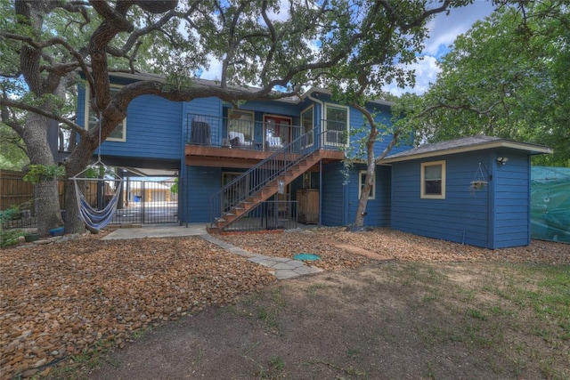 rear view of property with a wooden deck, stairs, and fence