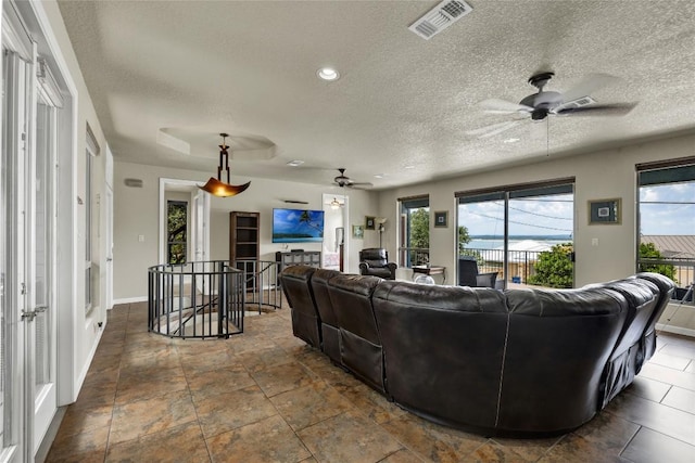 living area featuring a ceiling fan, baseboards, visible vents, recessed lighting, and a textured ceiling