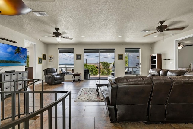 living area featuring visible vents, a textured ceiling, and ceiling fan