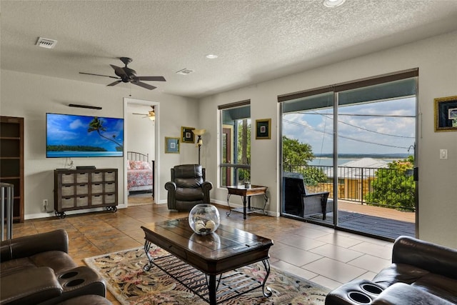 tiled living area featuring baseboards, visible vents, a textured ceiling, and a ceiling fan