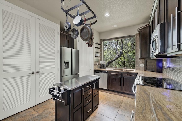 kitchen with a sink, tasteful backsplash, a textured ceiling, recessed lighting, and stainless steel appliances