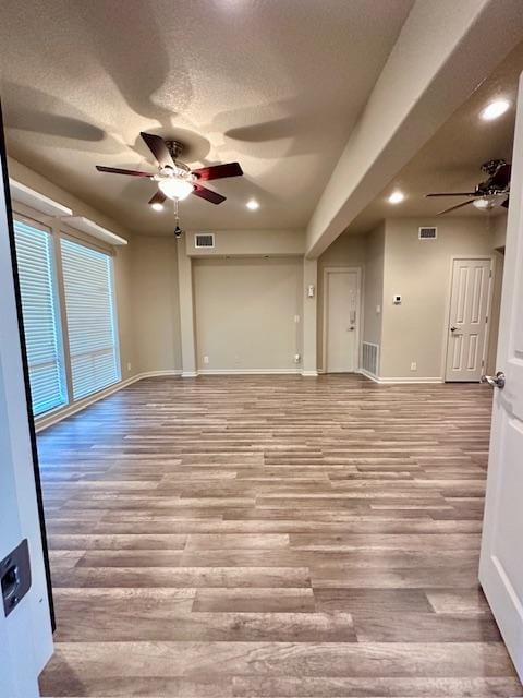 unfurnished room featuring a textured ceiling, baseboards, ceiling fan, and wood finished floors