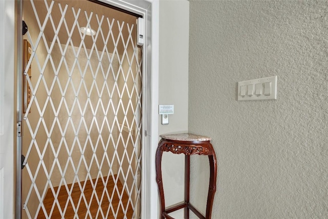 details featuring elevator, wood finished floors, and a textured wall