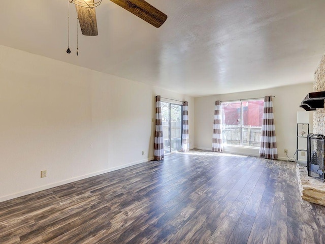 6905 Old Post Loop, Austin, TX 78744 - unfurnished living room with wood finished floors, a ceiling fan, and a stone fireplace
