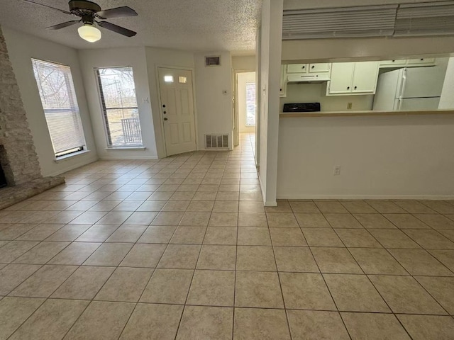 10616 Mellow Meadows Dr Unit 30-D, Austin, TX 78750 - kitchen with under cabinet range hood, freestanding refrigerator, light tile patterned floors, a textured ceiling, and ceiling fan