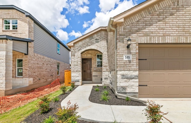 585 Tailwind Dr, Kyle, TX 78640 - property entrance featuring an attached garage, stone siding, and brick siding