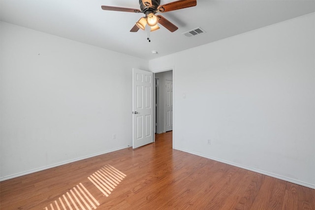unfurnished room featuring light wood-style floors, visible vents, baseboards, and ceiling fan