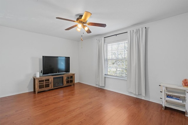 living room with baseboards, a ceiling fan, and wood finished floors