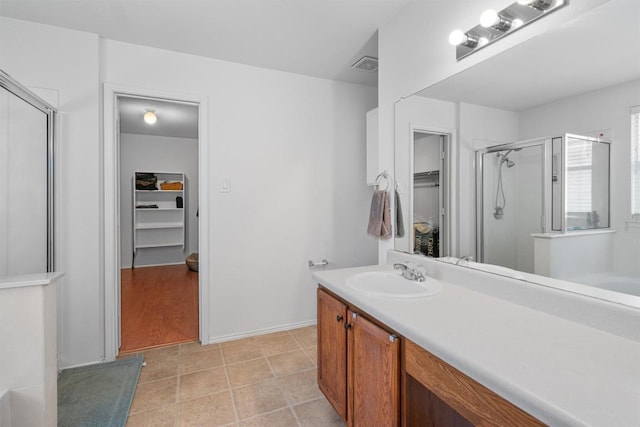 bathroom with vanity, a spacious closet, tile patterned floors, a shower stall, and visible vents