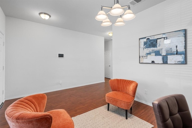 living area featuring a chandelier, visible vents, baseboards, and wood finished floors