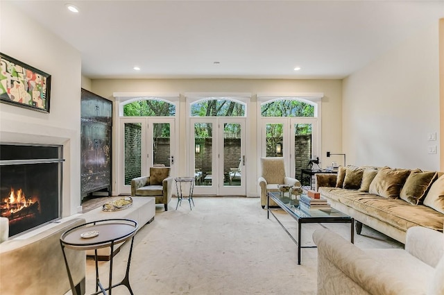 living room with recessed lighting, french doors, light colored carpet, and a lit fireplace