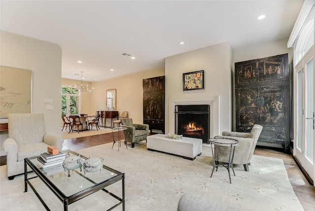 living room featuring a wealth of natural light, a chandelier, recessed lighting, and a lit fireplace