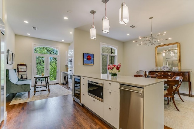 kitchen with beverage cooler, visible vents, dark wood finished floors, stainless steel appliances, and white cabinetry