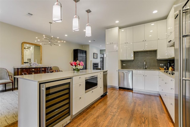 kitchen featuring stainless steel appliances, visible vents, beverage cooler, and white cabinetry