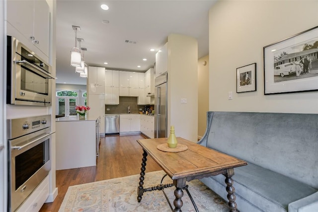 interior space featuring visible vents, backsplash, appliances with stainless steel finishes, white cabinets, and dark wood-style flooring