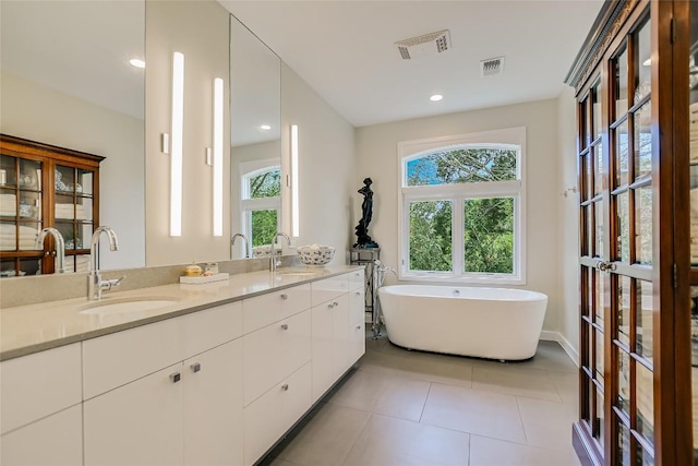 bathroom featuring a soaking tub, visible vents, and a sink