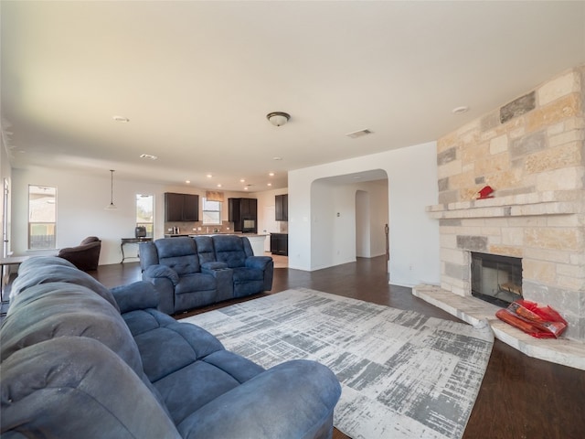 670 Landon Samuel Loop, Pflugerville, TX 78660 - living area with arched walkways, dark wood-style flooring, a stone fireplace, and recessed lighting