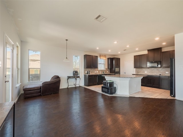 670 Landon Samuel Loop, Pflugerville, TX 78660 - kitchen with black microwave, freestanding refrigerator, dark brown cabinets, backsplash, and recessed lighting