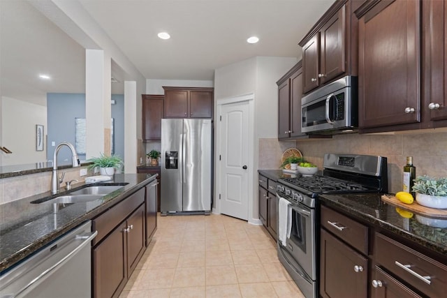 4706 Madrid Dr, Georgetown, TX 78628 - kitchen with appliances with stainless steel finishes, a sink, dark stone countertops, dark brown cabinetry, and tasteful backsplash