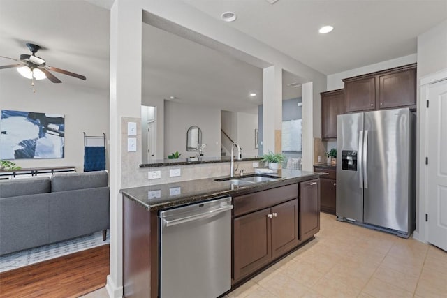 4706 Madrid Dr, Georgetown, TX 78628 - kitchen with stainless steel appliances, a sink, dark stone counters, dark brown cabinetry, and a ceiling fan